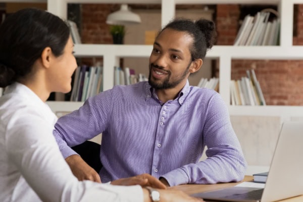 two people one coach one client seated in conversation at a table with a laptop