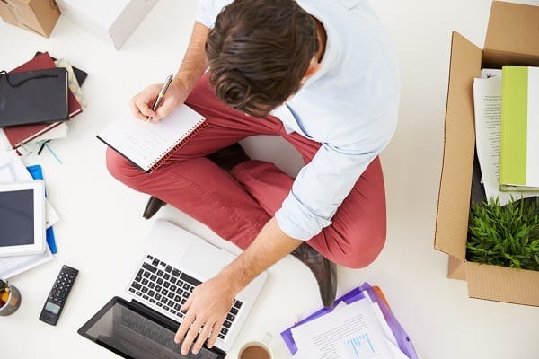 person sitting on the floor surrounded by office items as they start a business