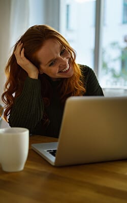 woman smiling looking at a laptop screen at a table