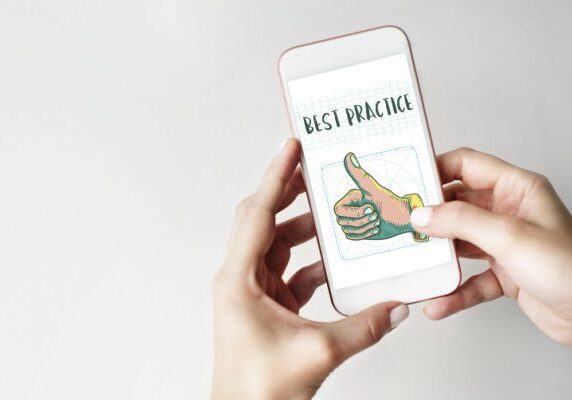 person holding a cellphone with a graphic on a thumbs up hand and the words best practice on the screen