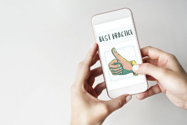 person holding a cellphone with a graphic on a thumbs up hand and the words best practice on the screen