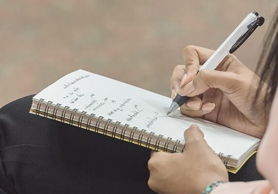 woman writing in notebook on her lap