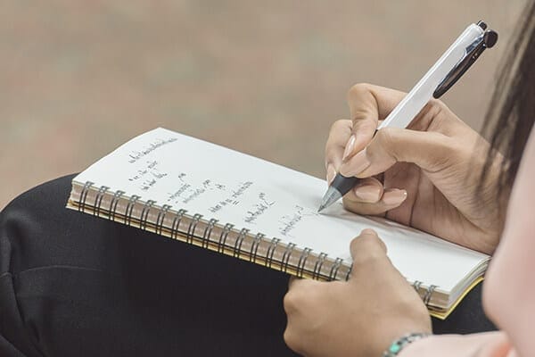 woman writing in notebook on her lap