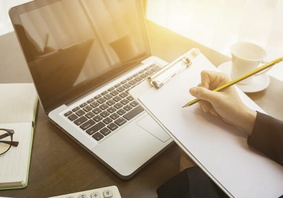 coach preparing for a session at a desk with a laptop note pad note book and coffee